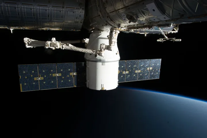 Astronauta che prepara un pasto a bordo della Stazione Spaziale Internazionale con buste di cibo liofilizzato.